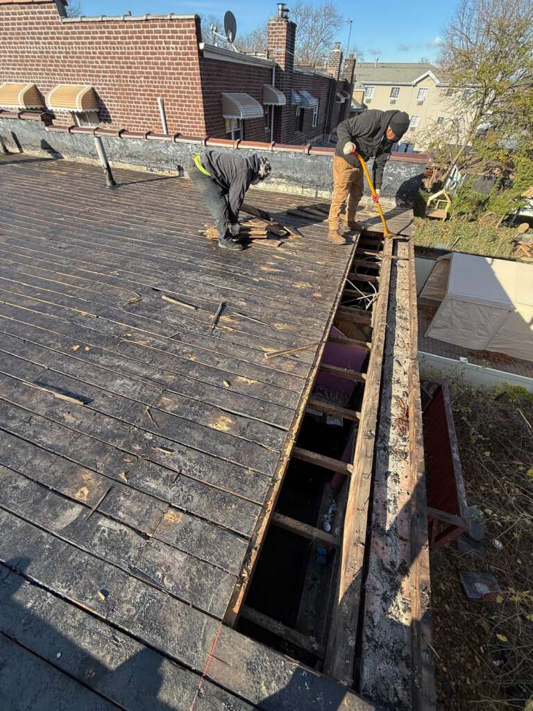 Flat roof installation in progress at Country Club, Bronx. Roofing team removing old roof, preparing deck, installing insulation and waterproof membrane for long-lasting protection