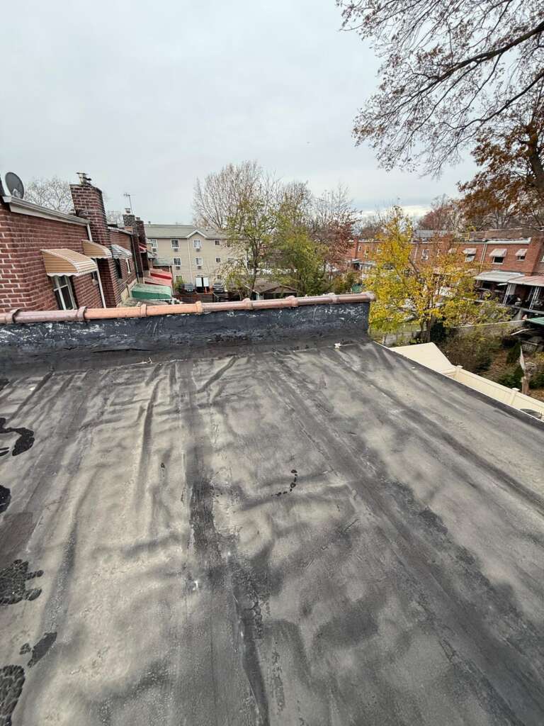 Flat roof installation in progress at Country Club, Bronx. Roofing team removing old roof, preparing deck, installing insulation and waterproof membrane for long-lasting protection