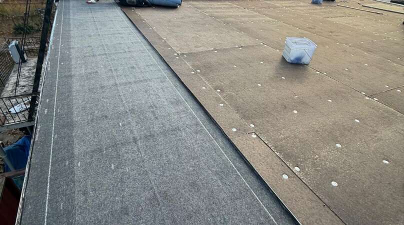 Flat roof installation in progress at Country Club, Bronx. Roofing team removing old roof, preparing deck, installing insulation and waterproof membrane for long-lasting protection